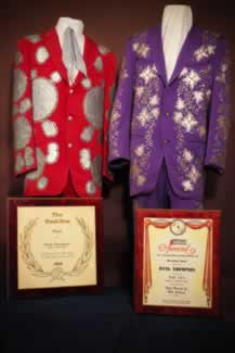 view of two of hank thompson's nudie suits awards and two awards